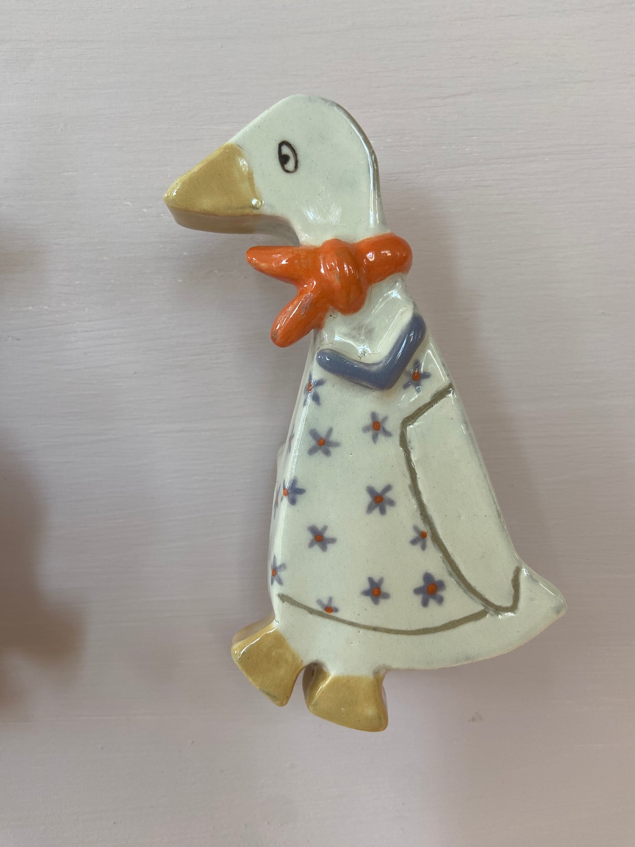 patere accroché à un mur représentant une petite oie avec un foulard orange et une robe étoilée