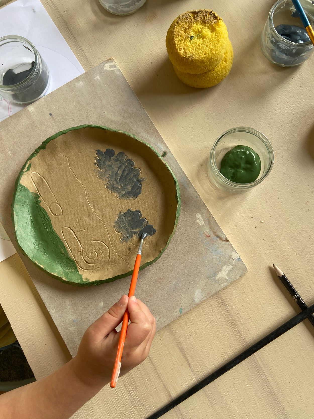 Emaillage d'une assiette au cours d'un atelier de poterie parents / enfants