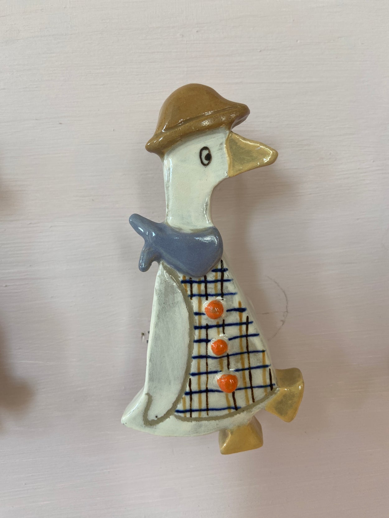 Patere représentant une oie avec un chapeau marron. L'oie à un foulard bleu et une chemise
