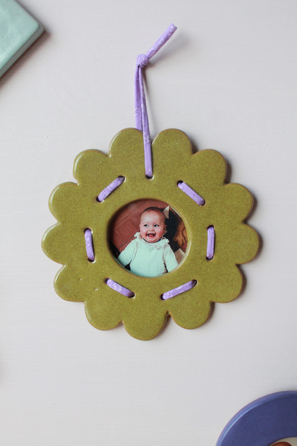 petit cadre photo vert dentele suspend à un mur par un fil violet