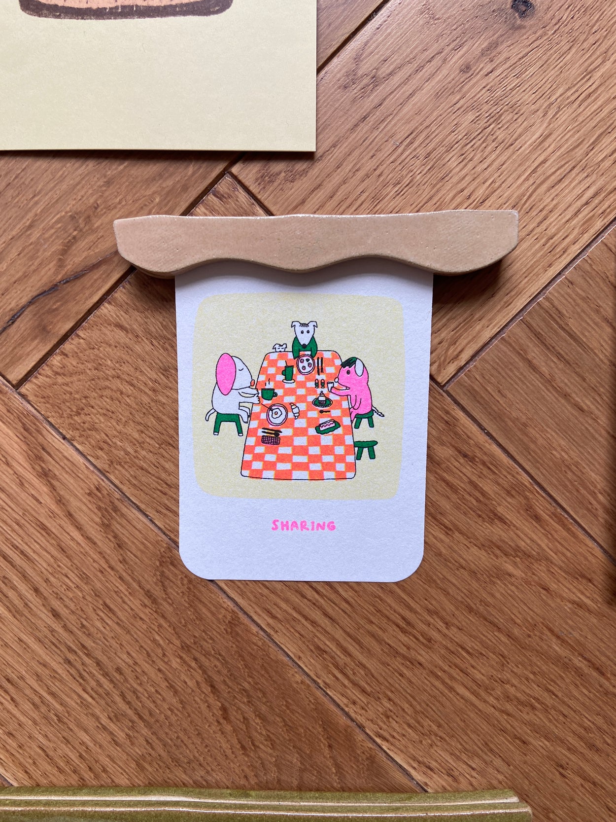 petit porte affiche beige contenant une affiche de Gisele et Rose représentant des animaux à table en train de partager un repas