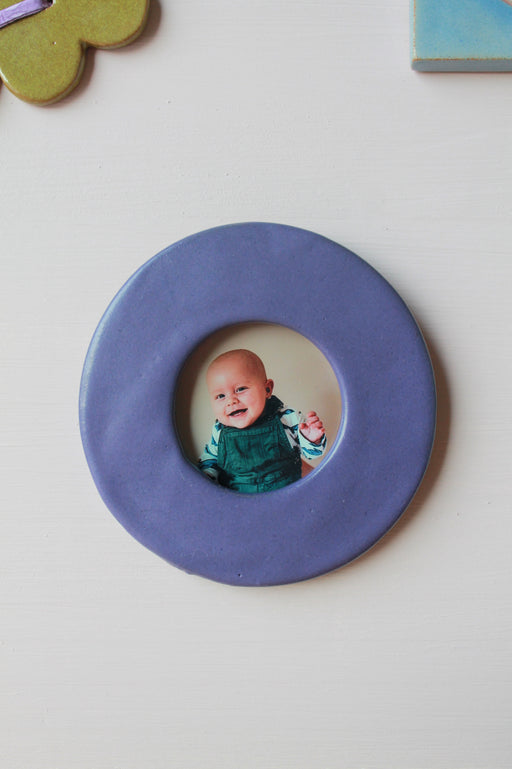 cadre photo rond et bleu avec au centre une photo de bébé souriant