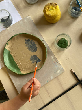Emaillage d'une assiette au cours d'un atelier de poterie parents / enfants