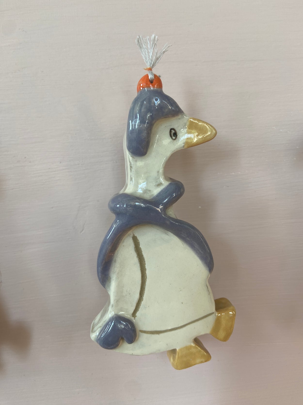 patere en forme d'oie accroché à un mur. 
L'oie à un bonnet et une écharpe et représente l'hiver