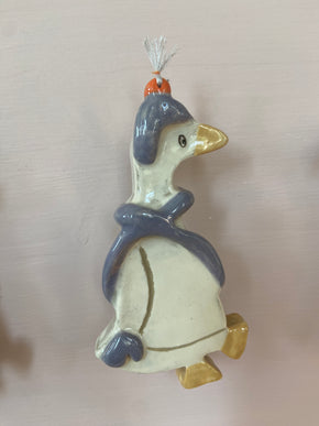 patere en forme d'oie accroché à un mur. 
L'oie à un bonnet et une écharpe et représente l'hiver