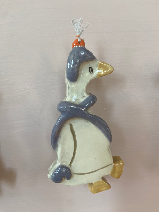 patere en forme d'oie accroché à un mur. 
L'oie à un bonnet et une écharpe et représente l'hiver