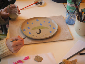L'image montre une assiette en cours de réalisation chez Florine est Micheline à Lille. 
Un parapluie jaune est dessiné dessus.